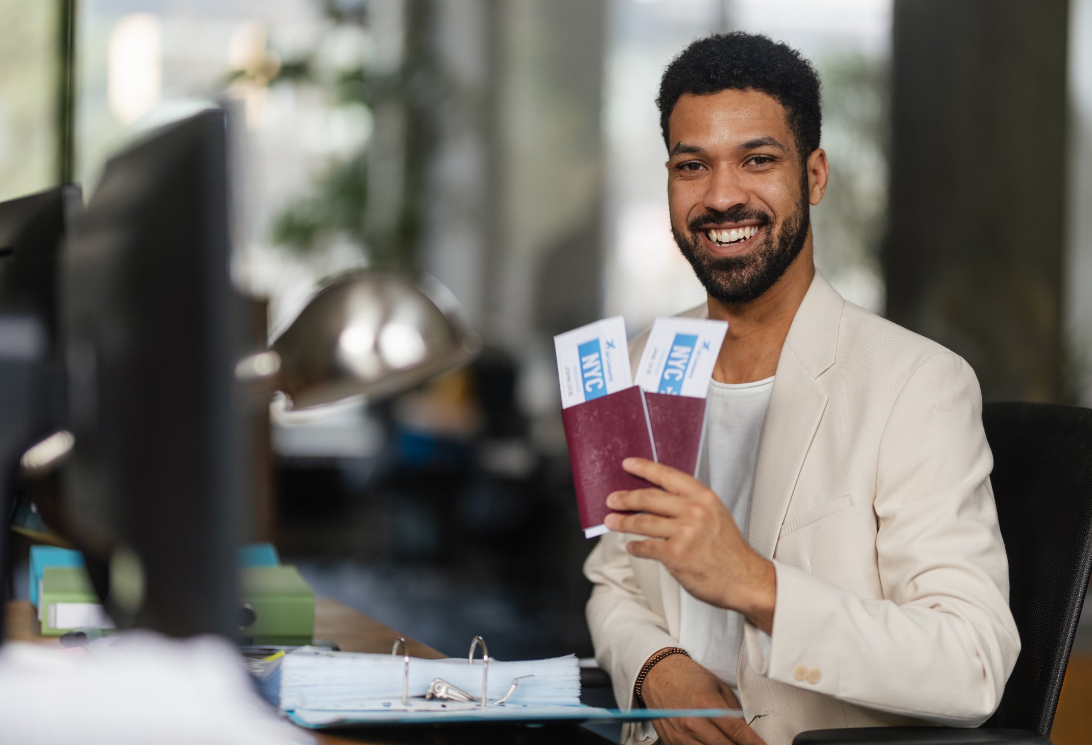 Young Happy Man Holding Plane Tickets in Office.