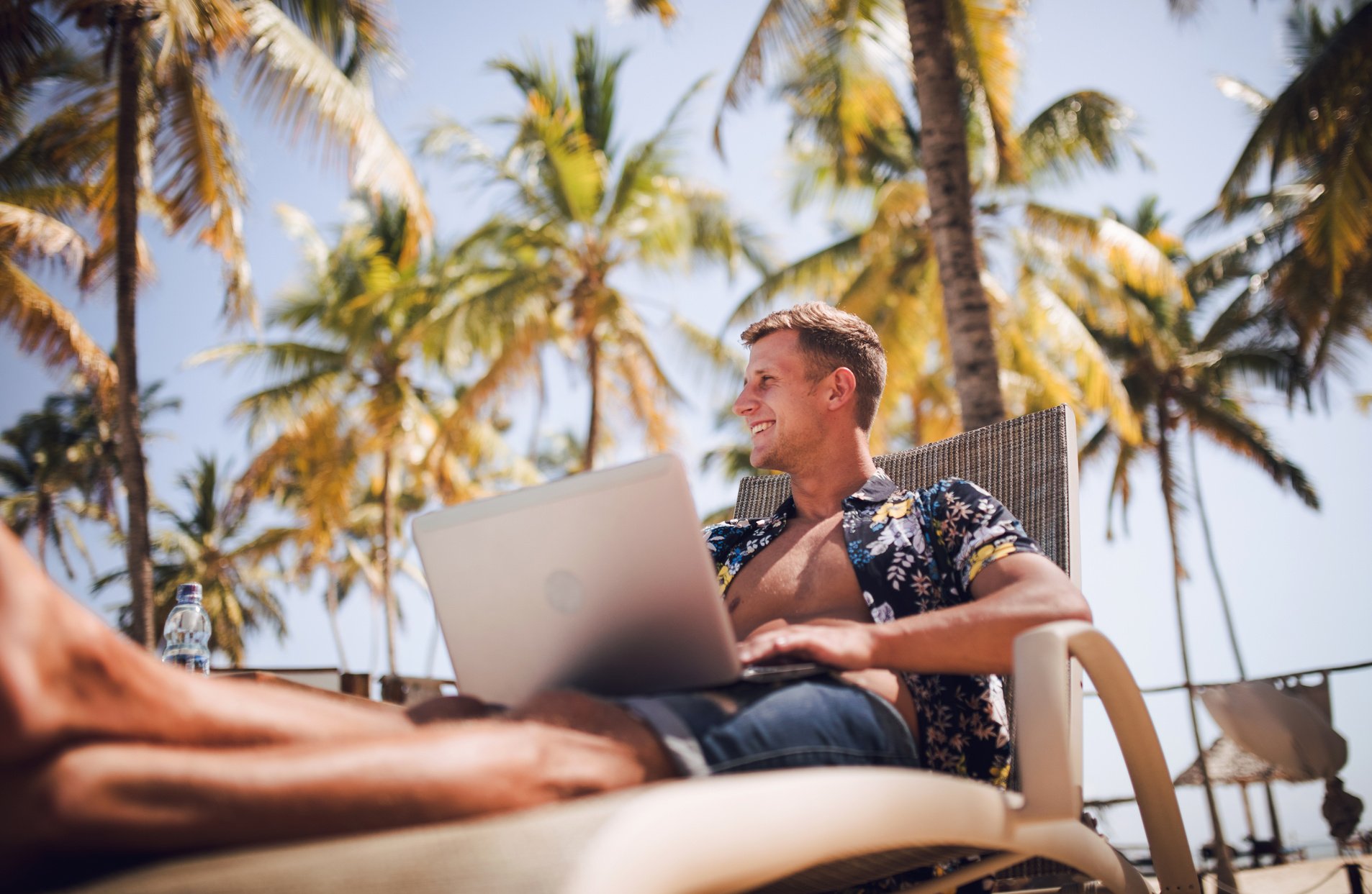 young digital nomad man at sea traveling with a computer